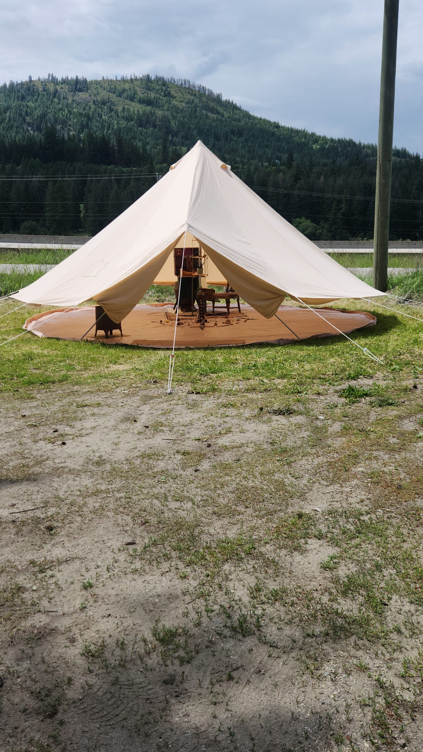 Sacred bell tent setup for a sound healing and meditation ceremony with a medicine wheel at the center, set against a lush green mountain in Shuswap, BC.