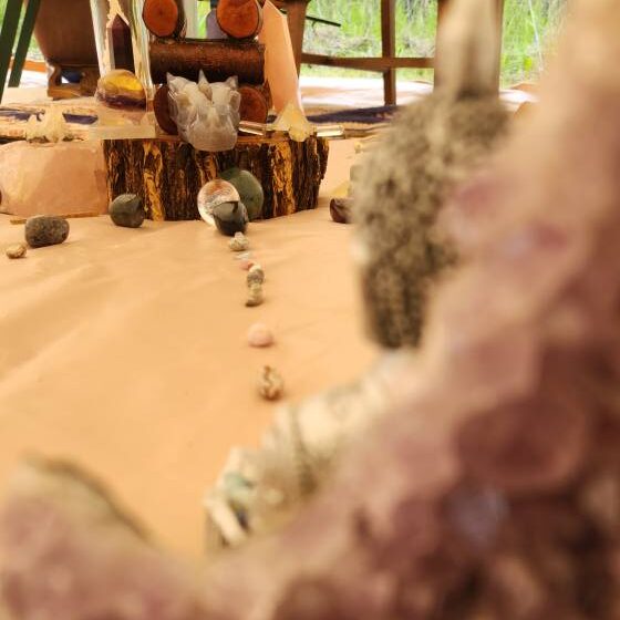 Close-up of amethyst crystal framing a sacred altar with a crystal path leading toward the center inside a bell tent used for Reiki and sound healing sessions