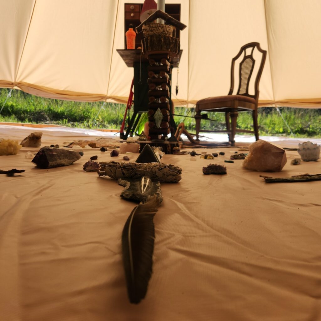 Inside view of a sacred Reiki space with crystals, feathers, and a healing altar at the center of a medicine wheel in a large bell tent near Salmon Arm, BC