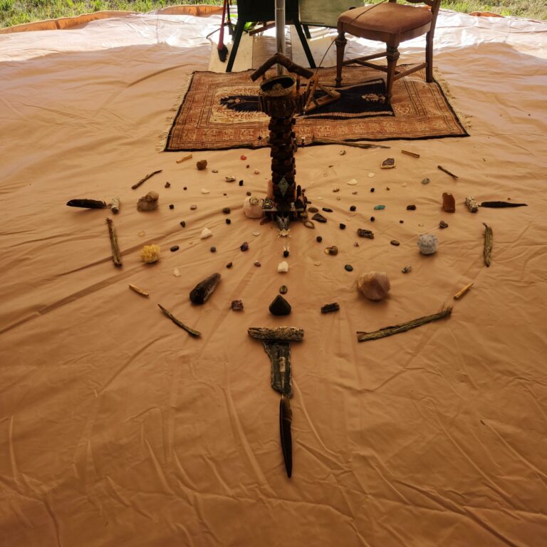 Sacred medicine wheel made of crystals, feathers, stones, and offerings arranged on the floor of a bell tent for Reiki and sound healing sessions near Salmon Arm, BC